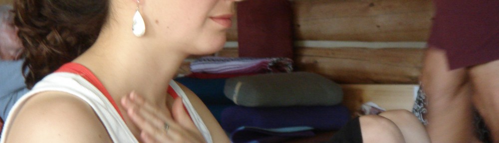 A woman sitting down with her hands on her chest.