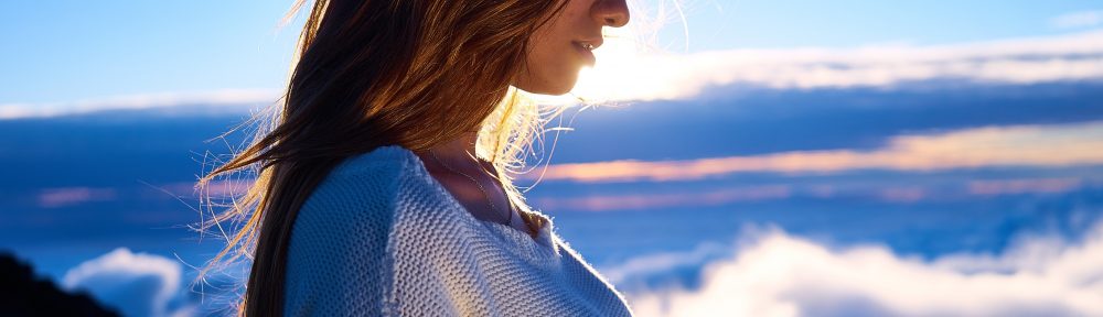 A woman standing in front of the sky with clouds.