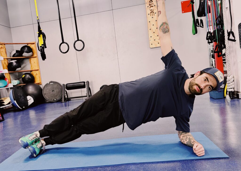 A woman is stretching on the floor with another person.