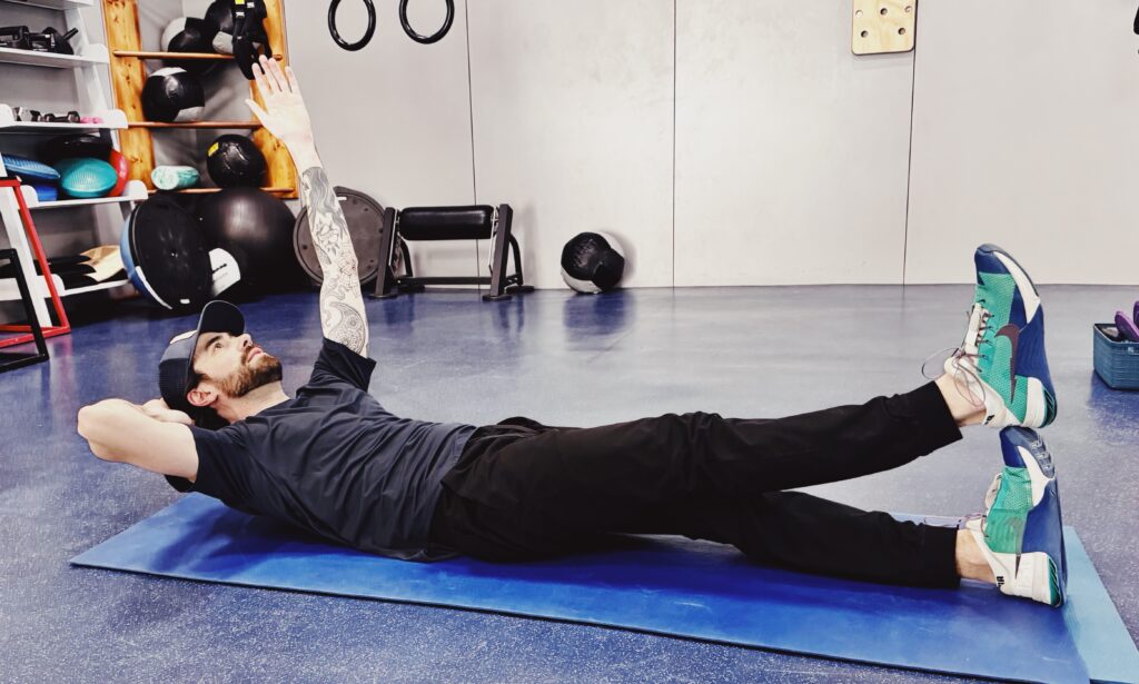 A woman is stretching on the floor with another person.