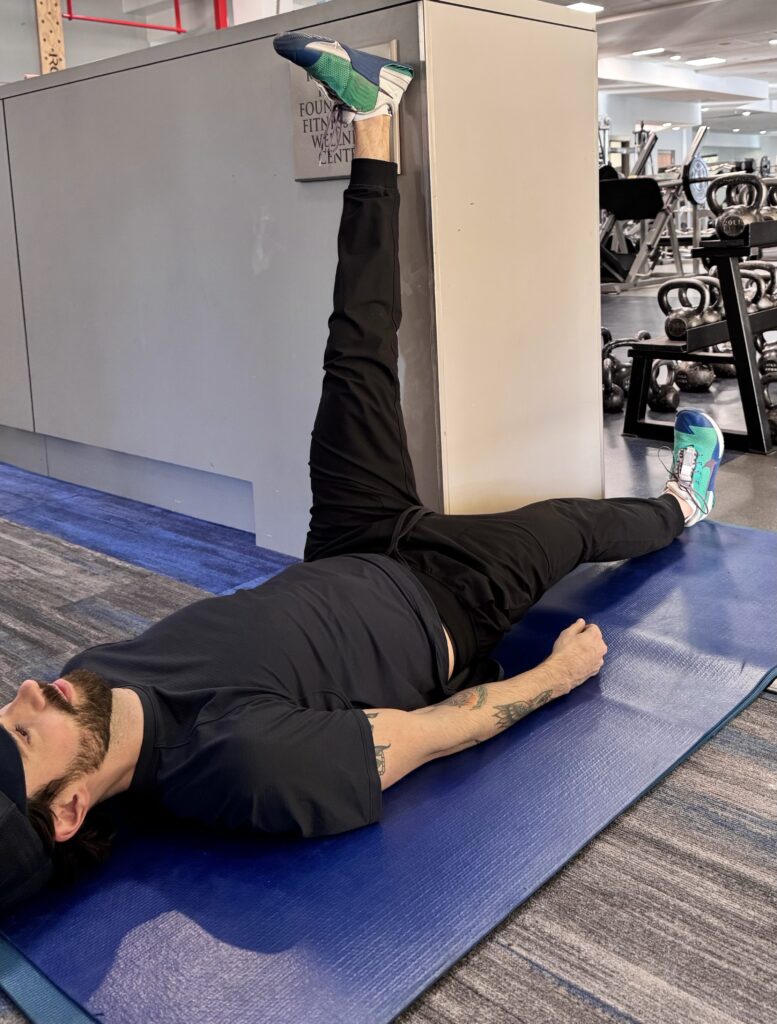 A woman is stretching on the floor with another person.