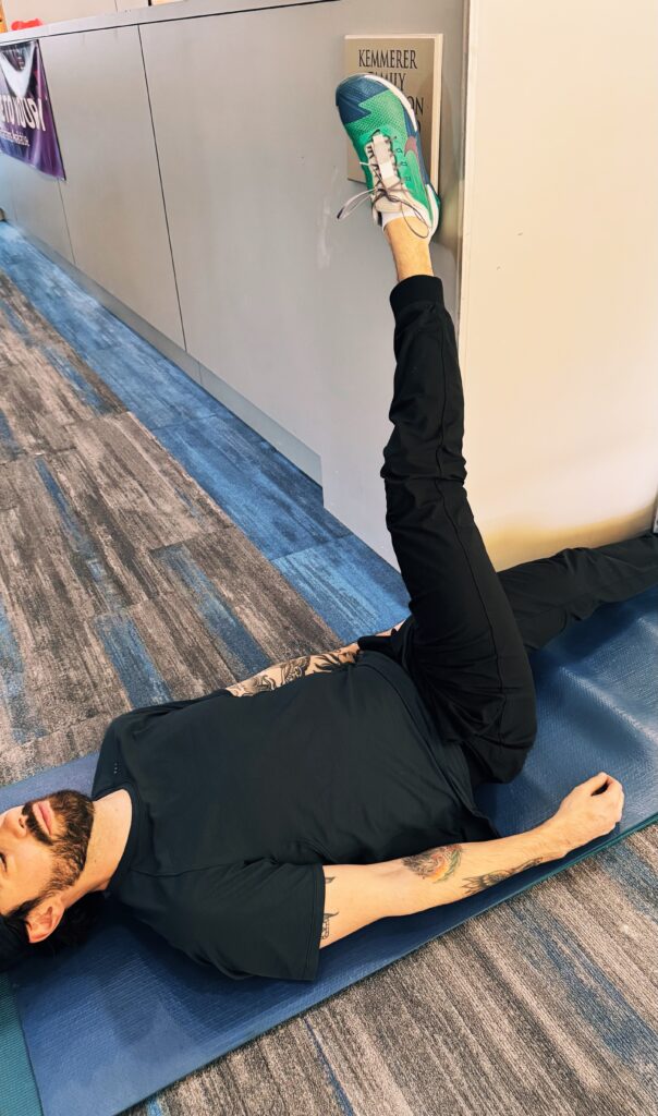 A woman is stretching on the floor with another person.