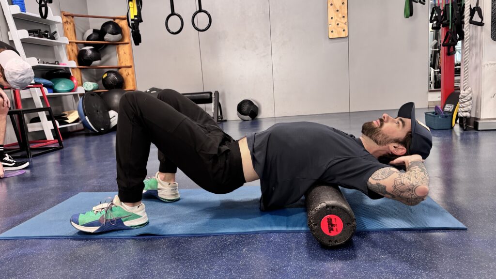 A woman is stretching on the floor with another person.