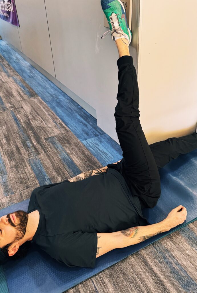 A woman is stretching on the floor with another person.