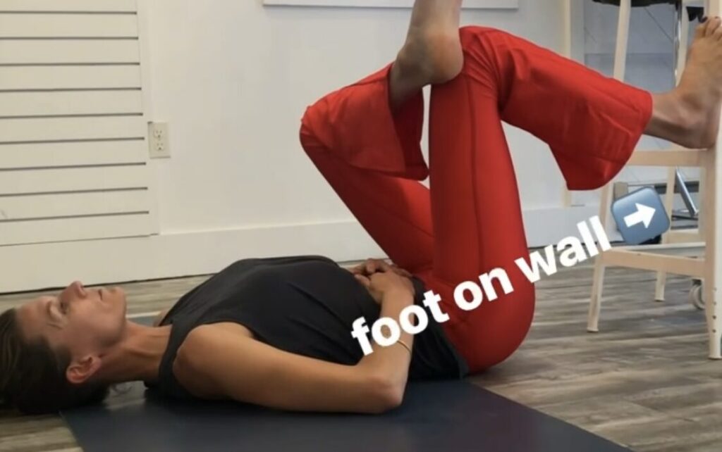A woman is stretching on the floor with another person.